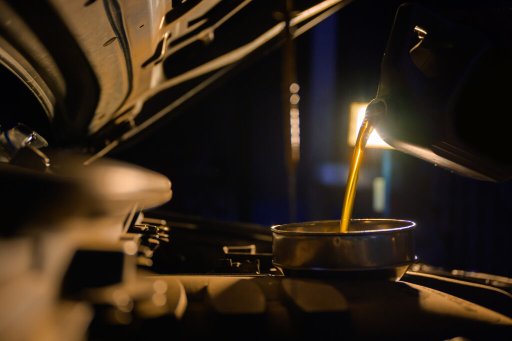 Auto mechanic pours car engine oil into the engine room. oil change at a repair shop or an interior car care center